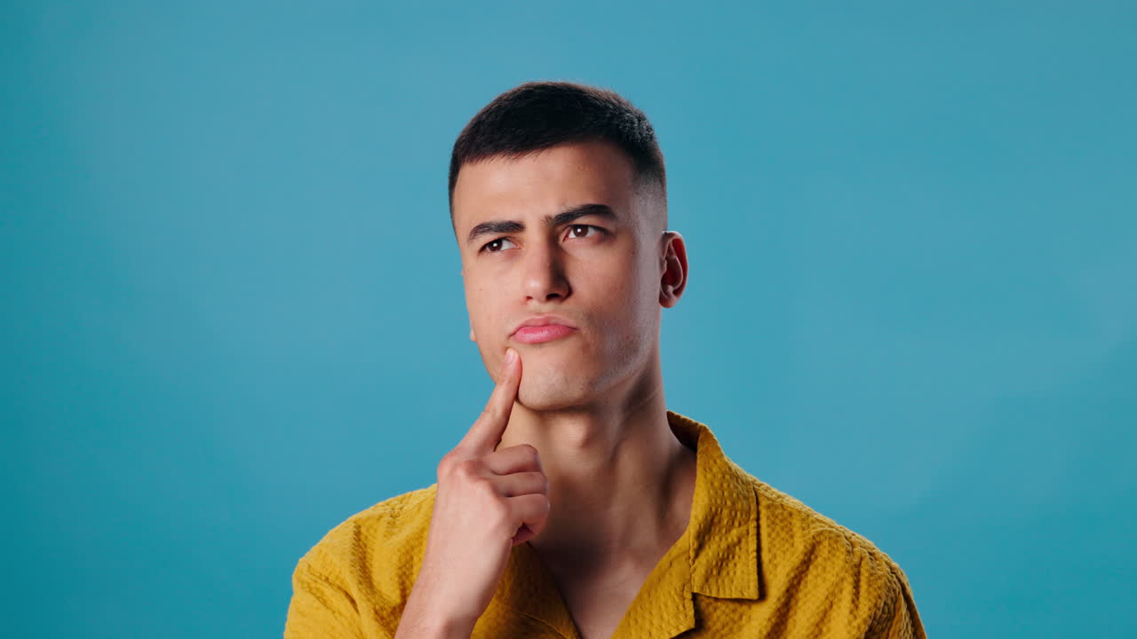 A thoughtful man in a yellow shirt contemplating