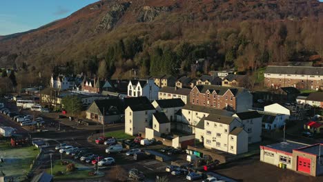 descending drone over aberfoyle village with craigmore hill in the background being revealed in scotland