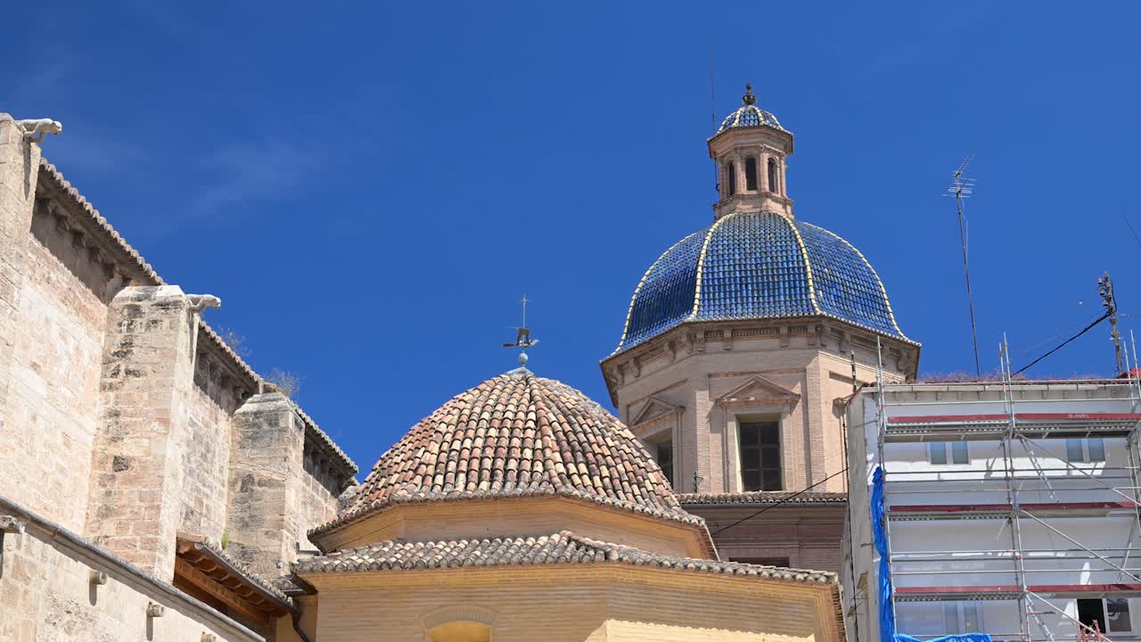 Una chiara vista della cupola piastrellata di blu e della facciata classica della basilica storica sotto un cielo azzurro brillante in un pomeriggio di primavera soleggiato.