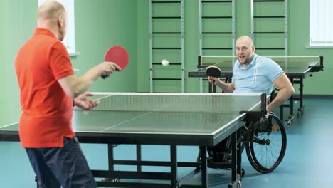 a man in a wheelchair plays ping pong. people with disabilities play table tennis. rehabilitation of the disabled. paralympic sport.