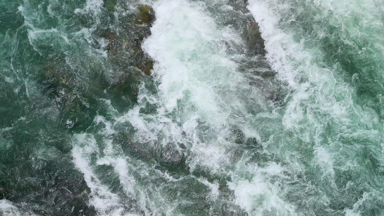 Drone captures turquoise river rapids crashing over rocks near Squamish, BC, with whitewater swirling and foamy waves.