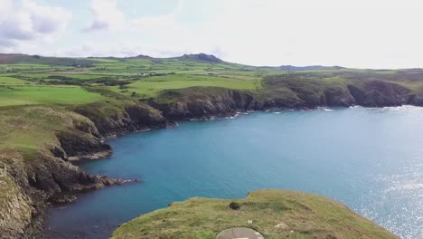 lighthouse high on headland island with blue sea beneath