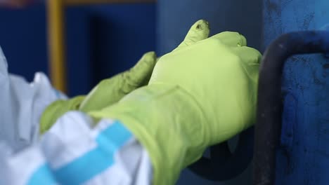 la mano del trabajador en guantes abre el cerrojo de la puerta del incinerador