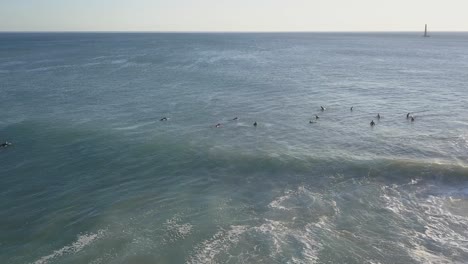 Aerial-view-of-surfers-in-an-amazing-and-unspoiled-beach-with-boat-in-background