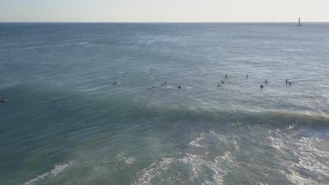 vista aérea de los surfistas en una playa increíble y virgen con barco en el fondo