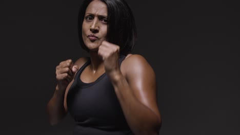 Studio-Portrait-Of-Mature-Woman-Wearing-Gym-Fitness-Clothing-Exercising-Sparring-At-Camera