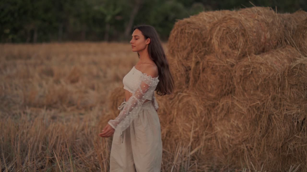 Donna spensierata che gira in un campo di fieno dorato al tramonto