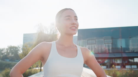 portrait of smiling caucasian young sporty woman in activewear standing in city park on sunny day