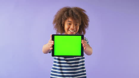 Retrato-De-Estudio-De-Un-Niño-Usando-Una-Tableta-Digital-Con-Pantalla-Verde-Sobre-Fondo-Púrpura