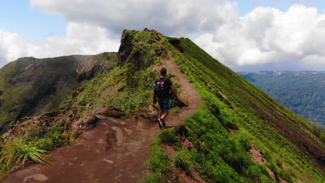 amazing scenery of a tourist walking near the crater of an active asian vulcano while steam is coming out from the side