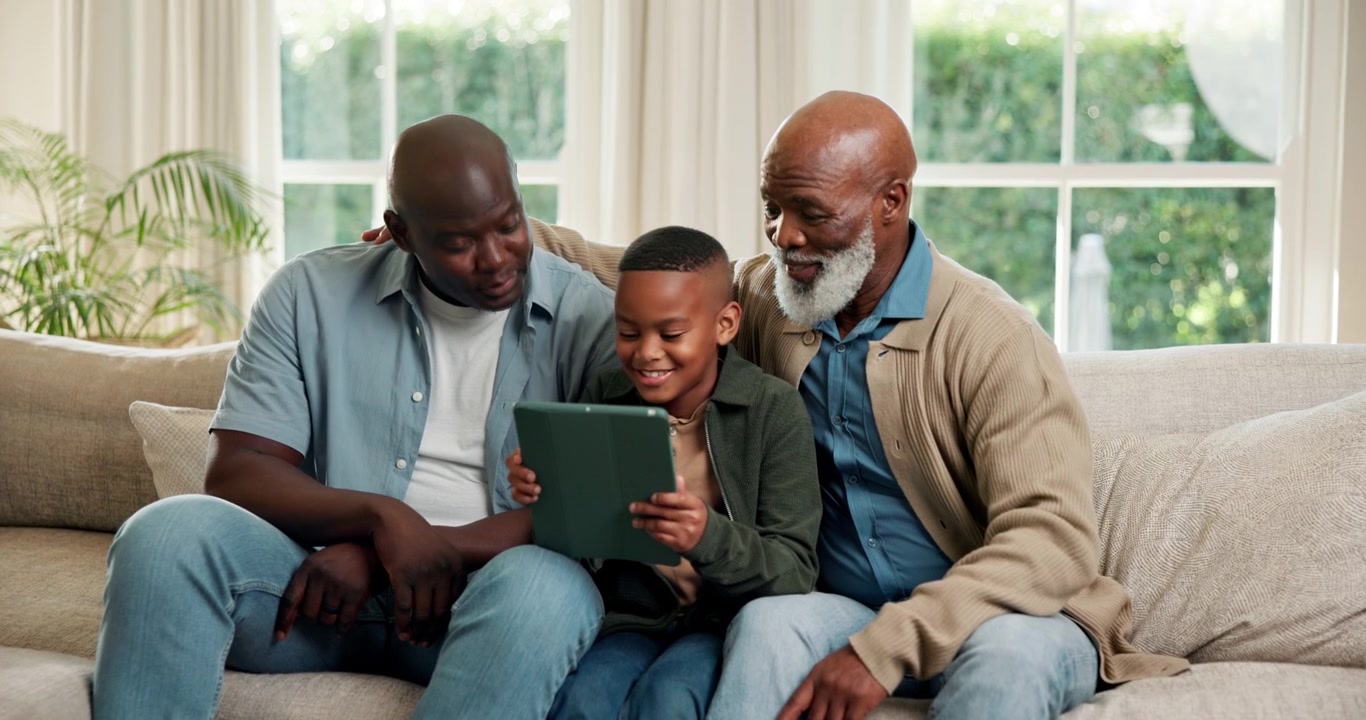 Three Generations of Men Using a Digital Tablet Together on a Sofa
