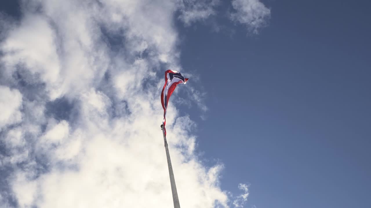 Vajande Thailands flagga på en stång med blå himmel och vita moln i bakgrunden