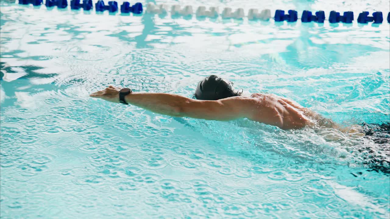 Competitive Swimmer Demonstrating Impressive Stroke Technique in a Crystal-Clear Pool with Rippled Water Surface During a Dynamic Training Session