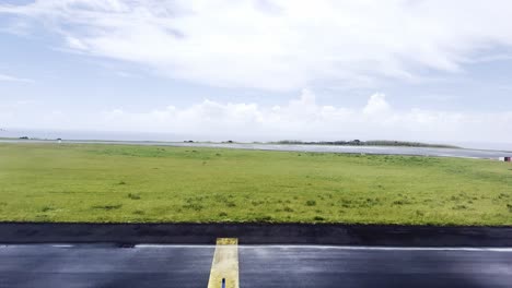 an empty runway after rain with lush green fields and cloudy skies, wet tarmac, aerial view