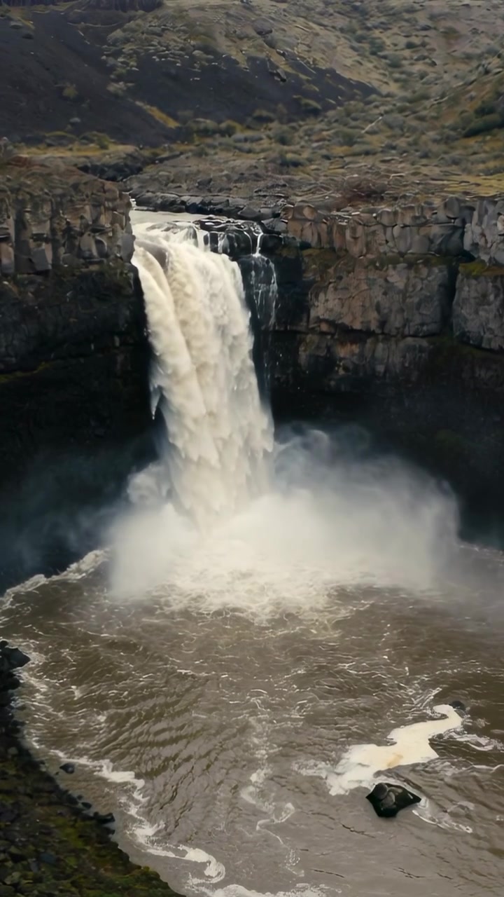 Video verticale: Cascata che si riversa, ricevendo il flusso del fiume su un bordo roccioso in una pozza nel canyon, creando nebbia