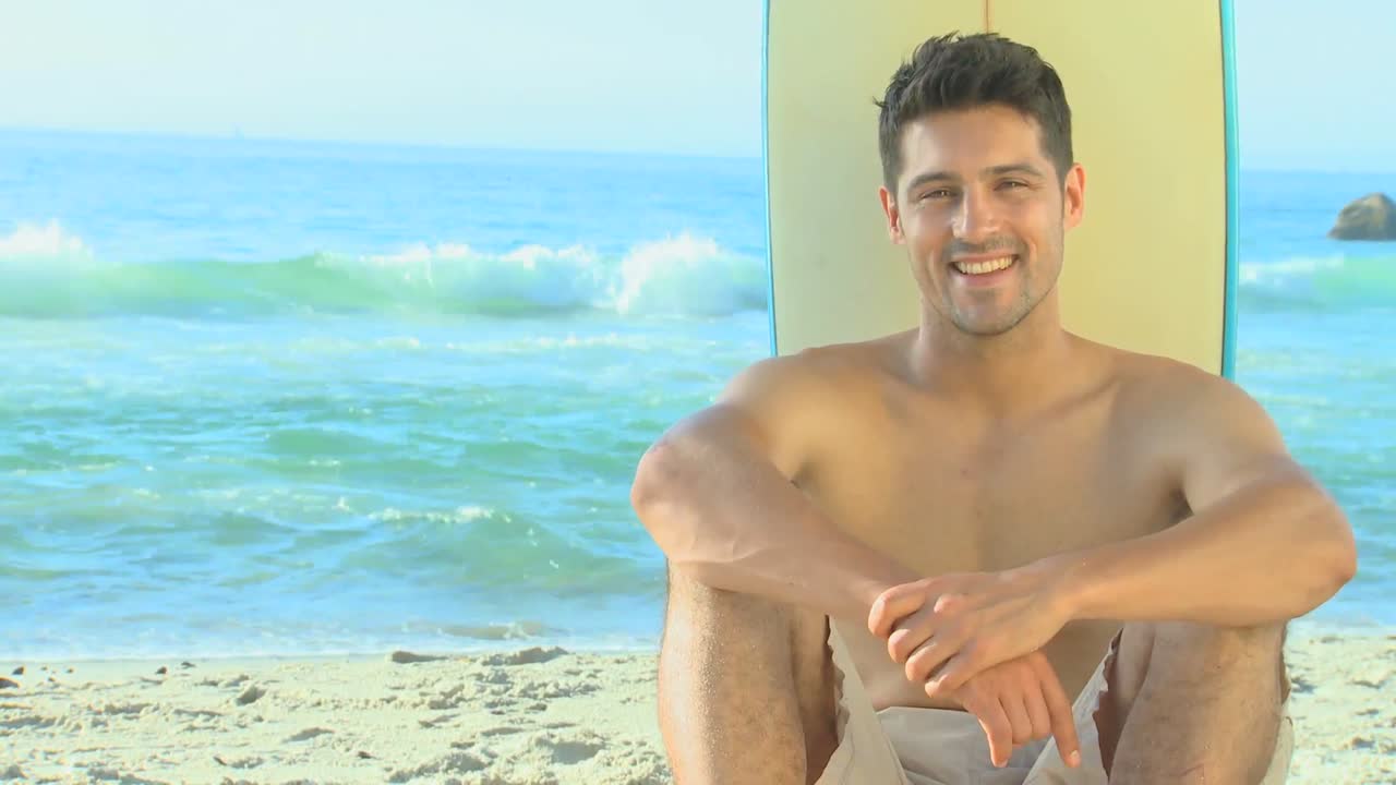 멋진 남자가 서프보드와 함께 포즈를 취하고 있다