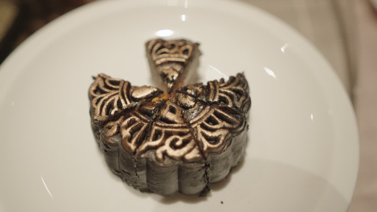 Person cutting a decorated mooncake