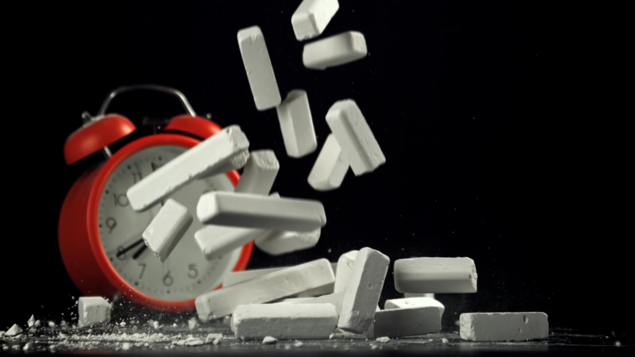 Slow Motion of Chalk Falling and Breaking Next to a Red Alarm Clock