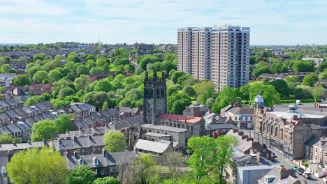 High-church-tower-stands-in-the-middle-of-a-residential-area-among-the-green-trees-in-Newcastle,-with-three-ultra-modern-residential-towers-in-the-background-on-a-sunny-day