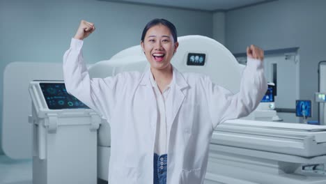asian woman doctor smile and flex muscle with mri machine in the hospital