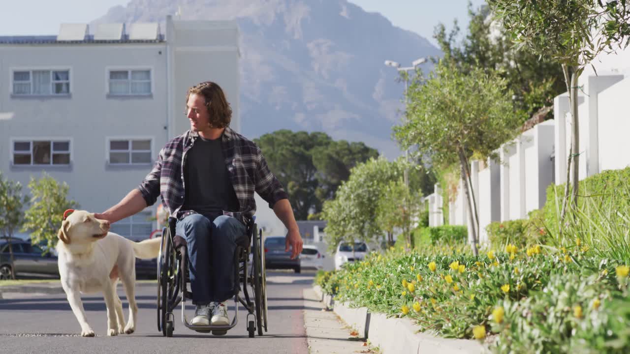 Smiling caucasian disabled man in wheelchair taking his pet dog for a walk in street