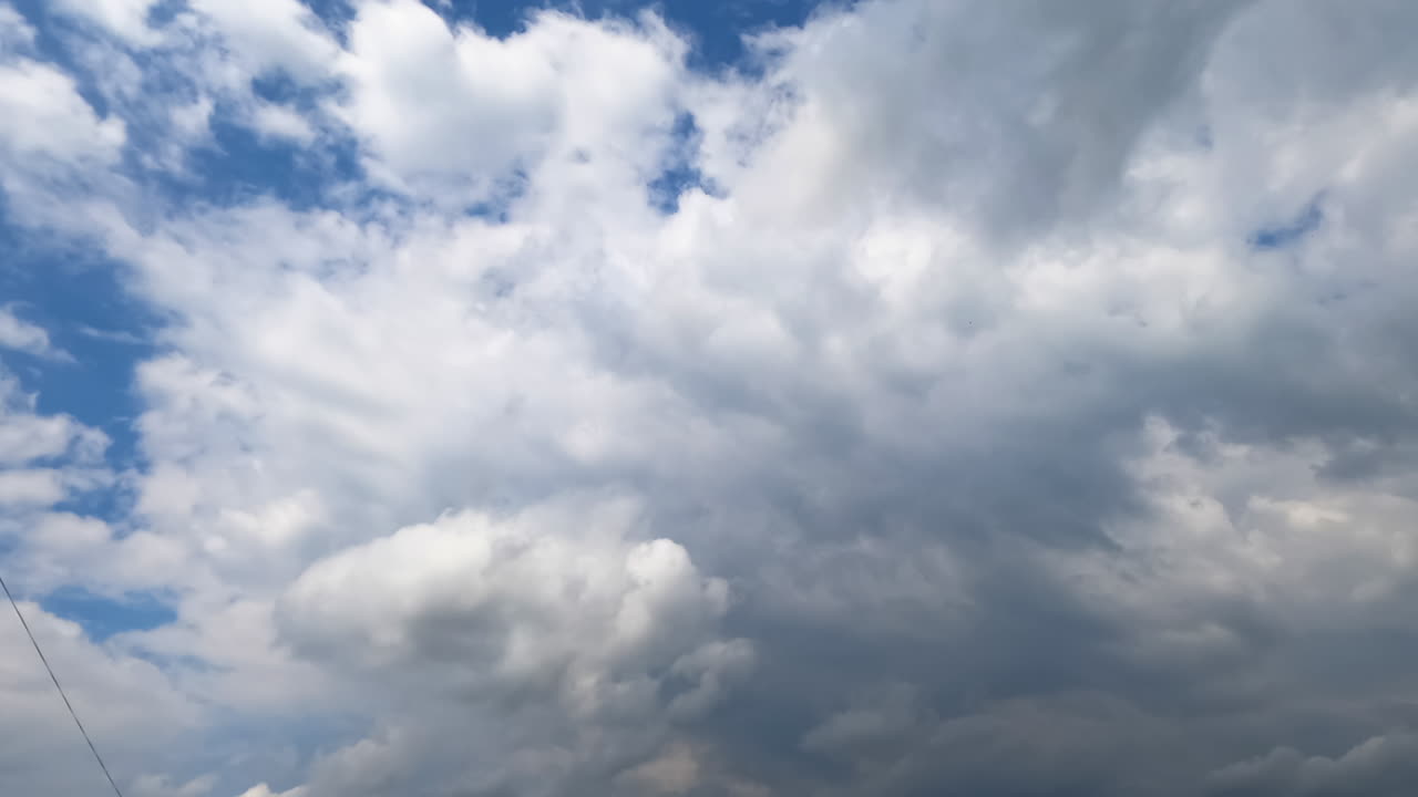 Accumulation of clouds in the blue sky. Separate white clouds transform into grey dark cloudscape. Low angle view. Timelapse.