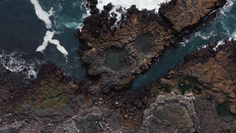 basalt rock coast in iceland with tranquil waves hitting shore, aerial