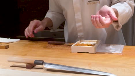 el chef prepara hábilmente el sushi uni en bangkok