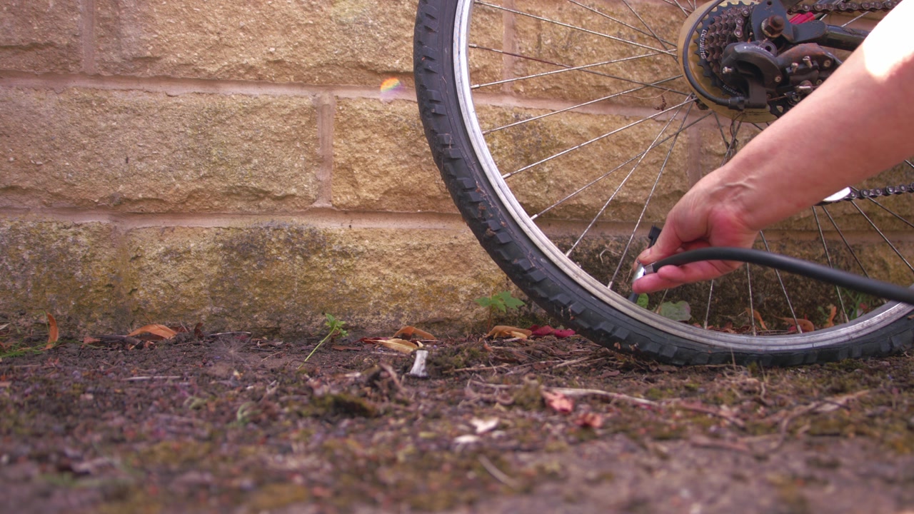 Cyclist pumping flat tyre on bicycle close up 4k slow motion shot selective focus