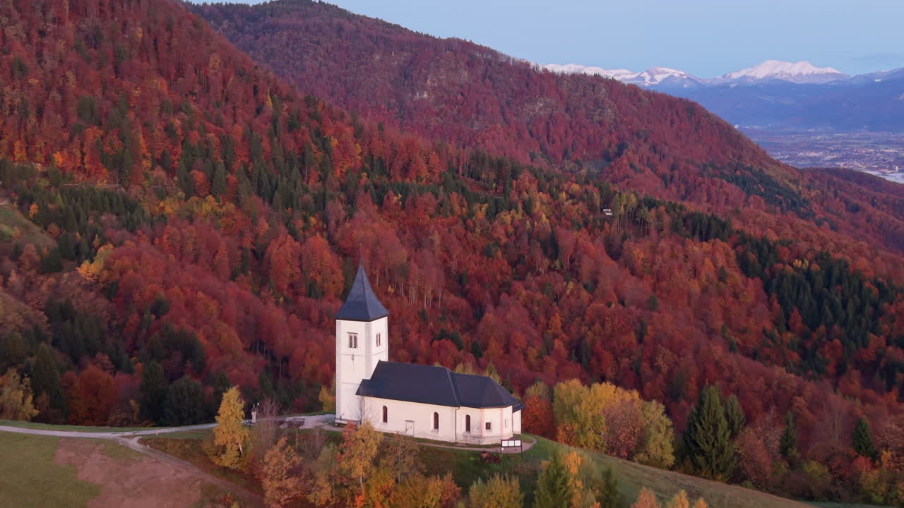 Aerial view of the Saints Primus and Felician Church at sunrise with colorful autumn foliage