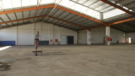 jinete de bmx en un almacén vacío