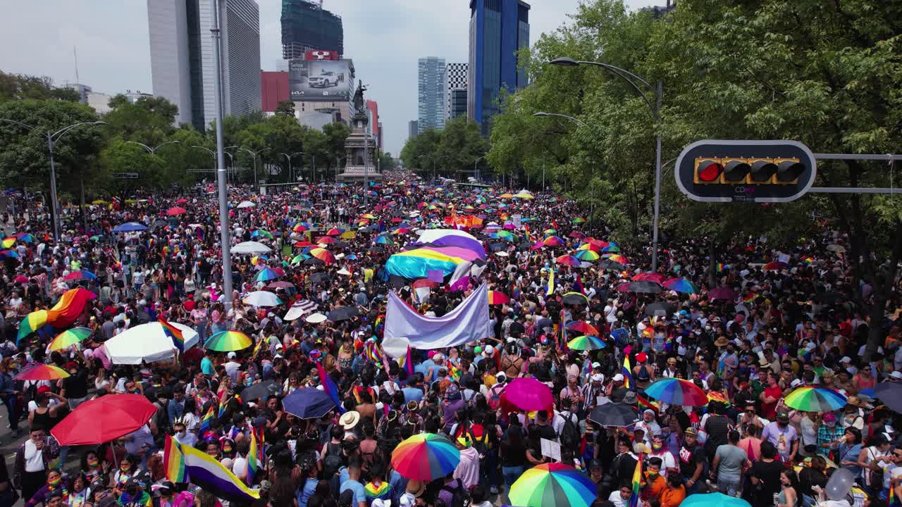 Vibrant Pride Parade with a Large Crowd and Rainbow Umbrellas in a City