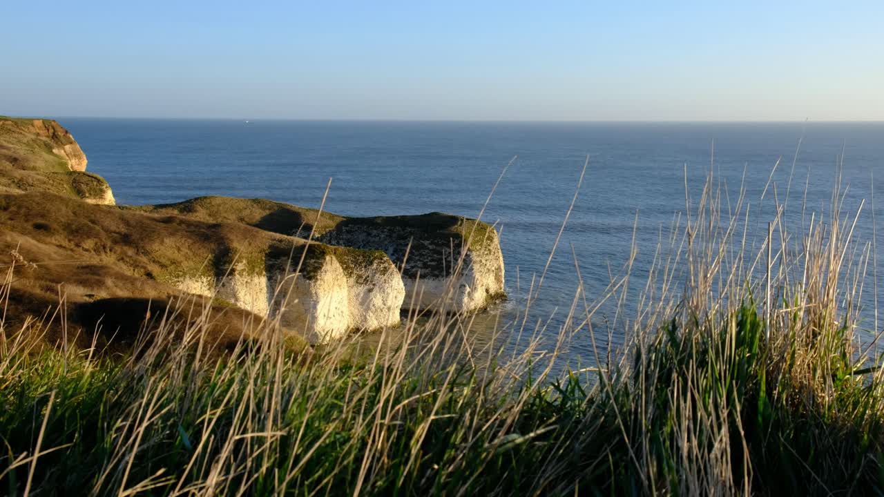 Dronevideo, der fanger den dramatiske skønhed ved Seven Sisters-kridtklinterne i East Sussex, England. De hvide klinter er belyst af den gyldne solnedgang og står i kontrast til det dybblå hav og himmel.