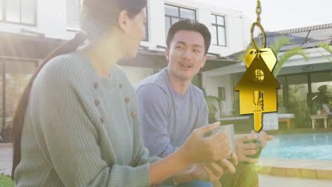 animation of gold house key and key fob over happy diverse couple in garden at home