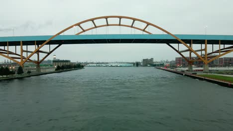 Aerial-drone-footage-of-Hoan-Bridge-in-downtown-Milwaukee-on-gloomy-day,-shot-from-river's-perspective