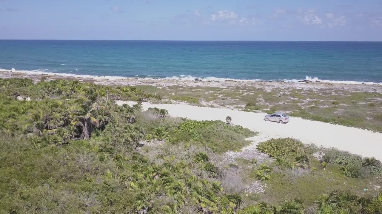 coche conduciendo en un camino de tierra a la orilla del mar