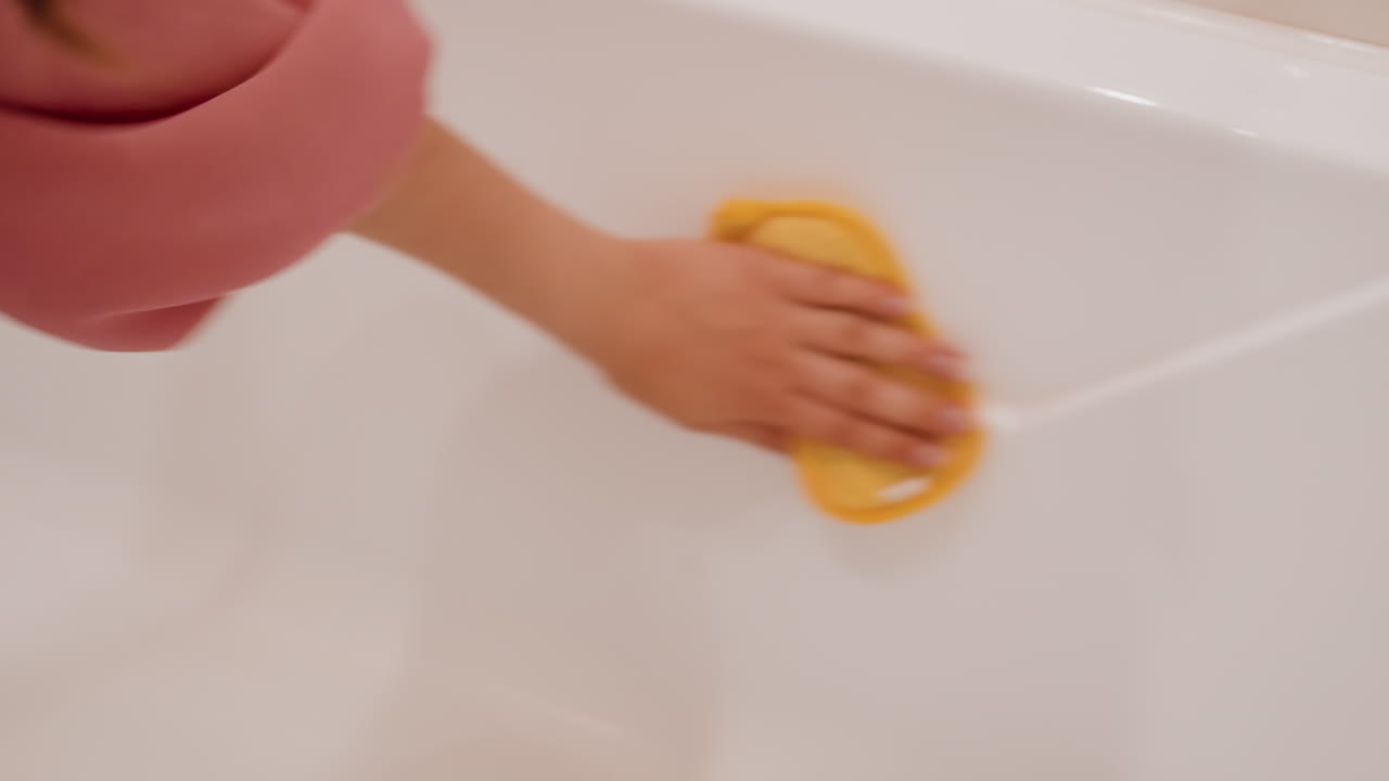 Scrubbing Tub With Sponge Action, Applying Circular Motions To Eliminate Bathroom Stains, Thoroughly Cleaning Bathroom Bathtub By Scrubbing Stains With Yellow Sponge In Circular Movements