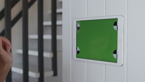 young woman using wall-mounted tablet with green screen