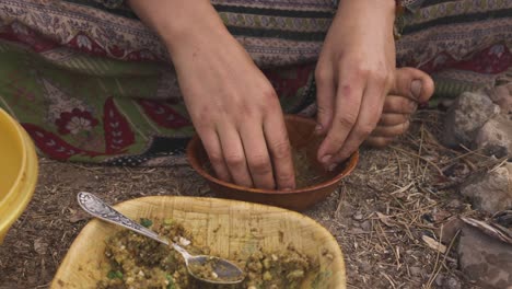 mujer indígena preparando comida con las manos mientras se sienta en el suelo