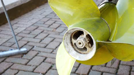 Yellow-metal-yacht-boat-propeller-rotor-blades-under-maintenance-vessel-in-shipyard-closeup-dolly-right