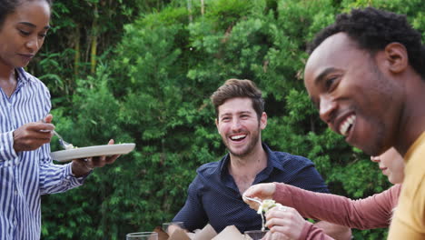 Mujer-Sirviendo-A-Un-Grupo-De-Amigos-Multiculturales-En-Casa-En-La-Mesa-Disfrutando-De-La-Comida-En-Una-Fiesta-En-El-Jardín-De-Verano