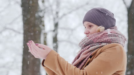 a woman catches snowflakes in her palms rejoices in the arrival of winter