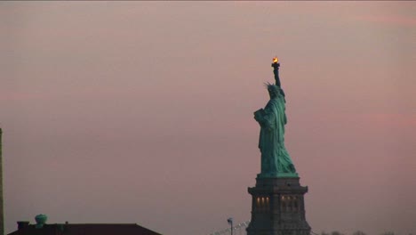 a striking view of the statue of liberty against a pale pink sky