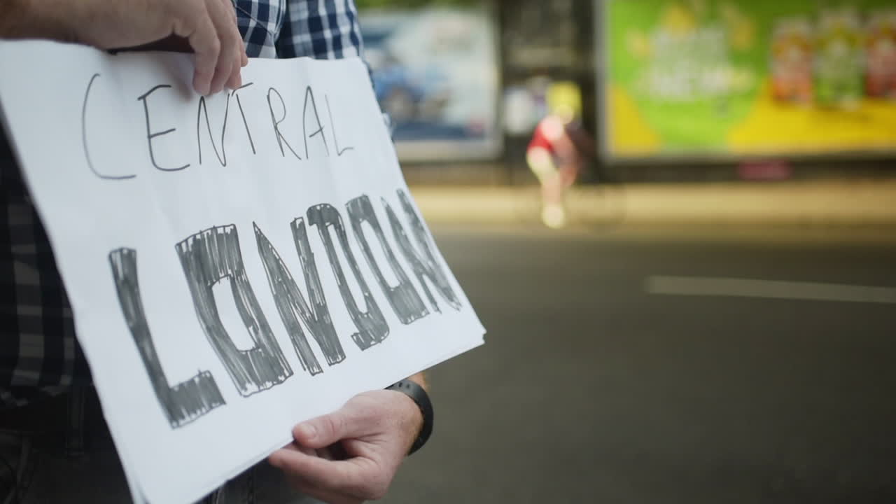 Close up hands of hitchhiker hold sign that says Central London