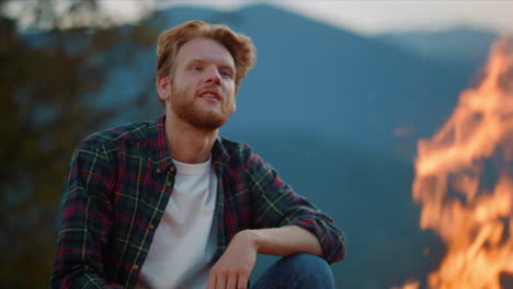 adventurous man look fire burning on cozy evening. camper rest in mountains.