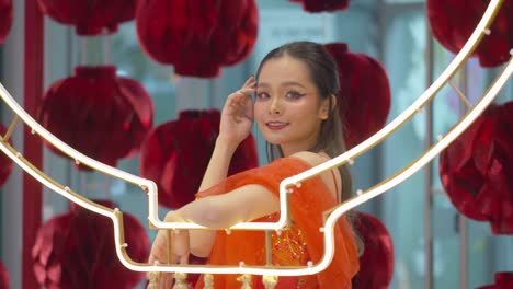 Asian-woman-with-traditional-red-dress-and-makeup-poses-by-the-paper-lanterns-as-she-celebrates-the-Chinese-New-Year---static-slow-motion