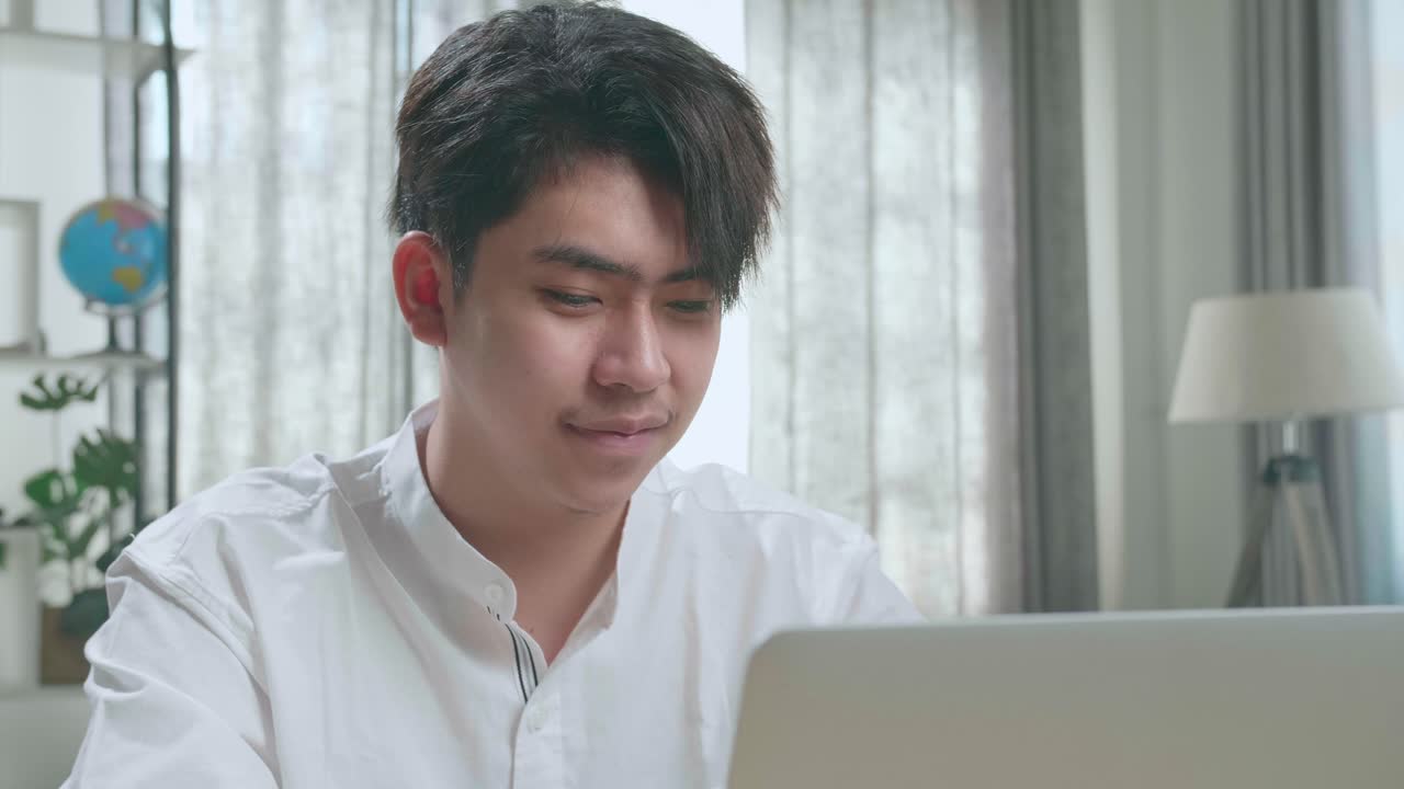 Close Up Of A Happy Asian Man Student Using Computer To Study Online At Home