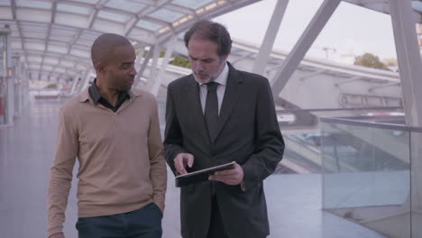 professional coworkers with digital tablet walking during discussion