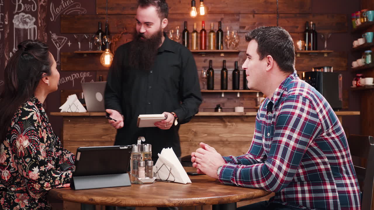 Couple in a restaurant being served by a waiter