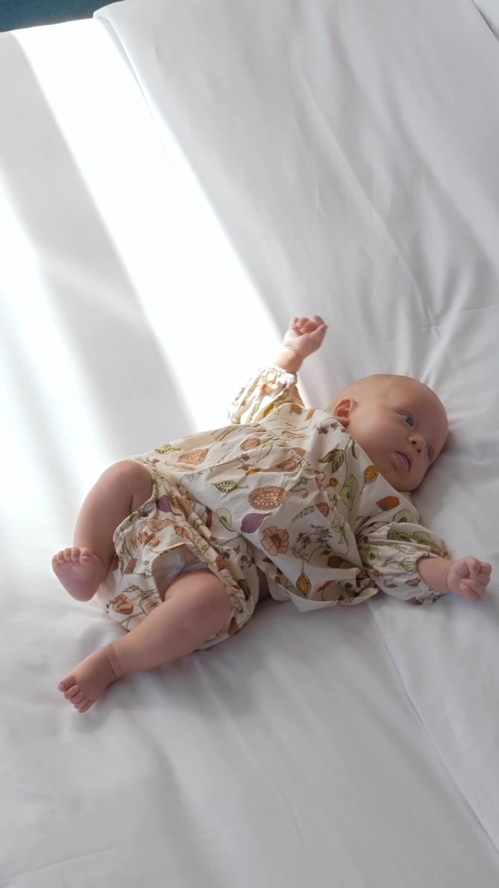 Adorabile bambina su biancheria da letto bianca